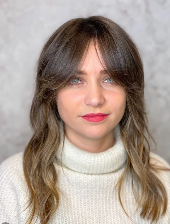 Brigitte Bardot face-framing bangs parted slightly in the middle, blending into layered hair for a timeless, voluminous, effortless look.