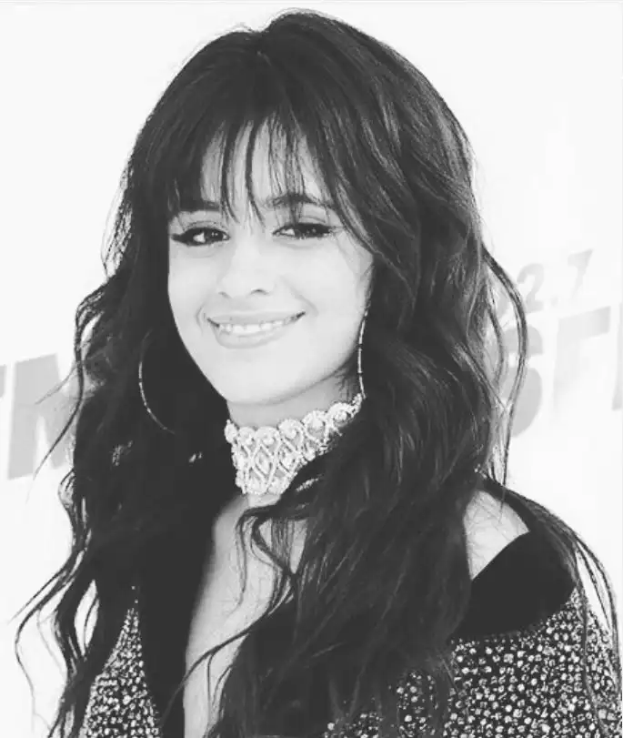 Camila Cabello feathered bangs softly layered across the forehead, blending seamlessly into long hair for a light, airy, feminine style.