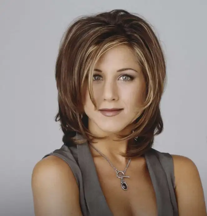 Jennifer Aniston side layered bangs blending into soft layers, creating a voluminous, polished hairstyle perfect for everyday wear.