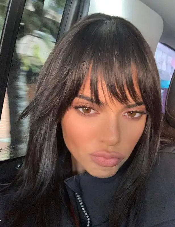 Kendall Jenner soft curtain fringe with long, face-framing layers, creating a sleek, polished hairstyle with subtle volume and symmetry.