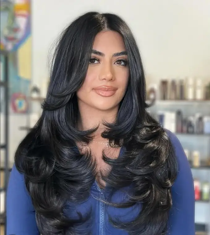 Long layered hairstyle with side swept bangs for round face slimming effect