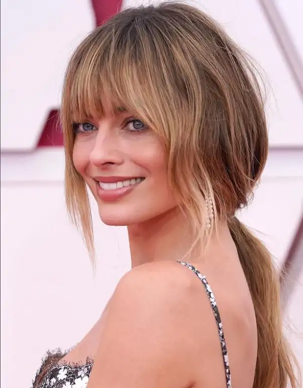 Margot Robbie blended bangs seamlessly flowing into long layers, creating a soft, natural hairstyle with effortless elegance.