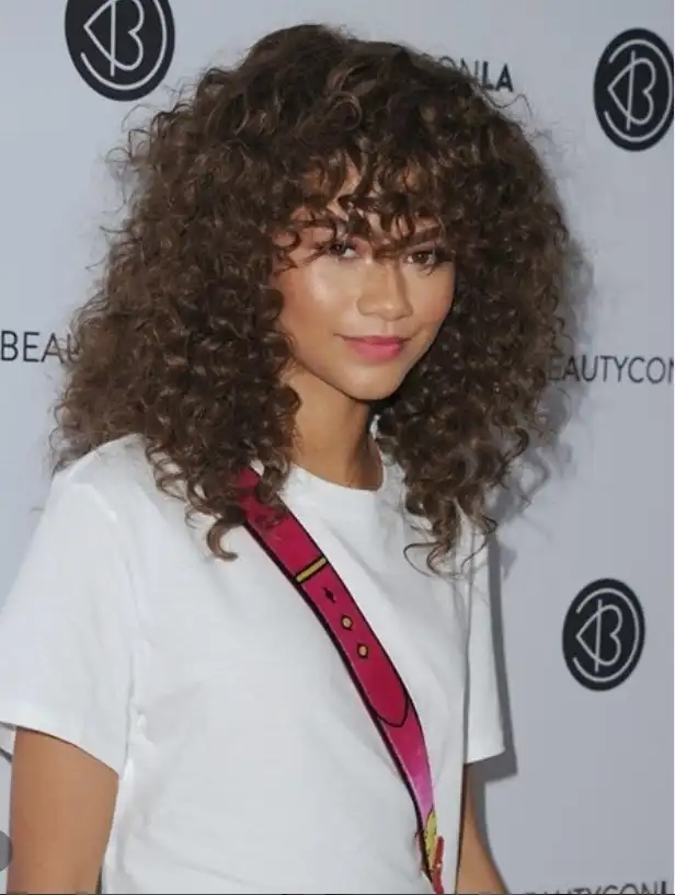 Zendaya curly bangs with natural volume and defined texture, framing the face beautifully and enhancing natural curls with a bold yet soft finish.