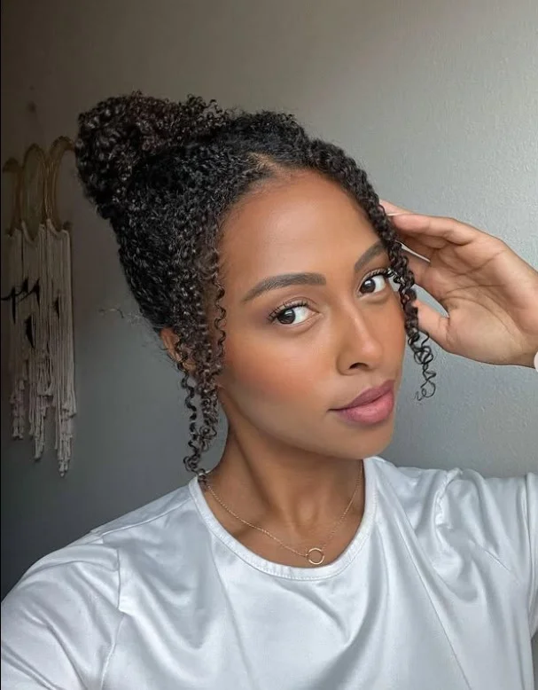 Curly bun hairstyle with side bangs voluminous soft texture