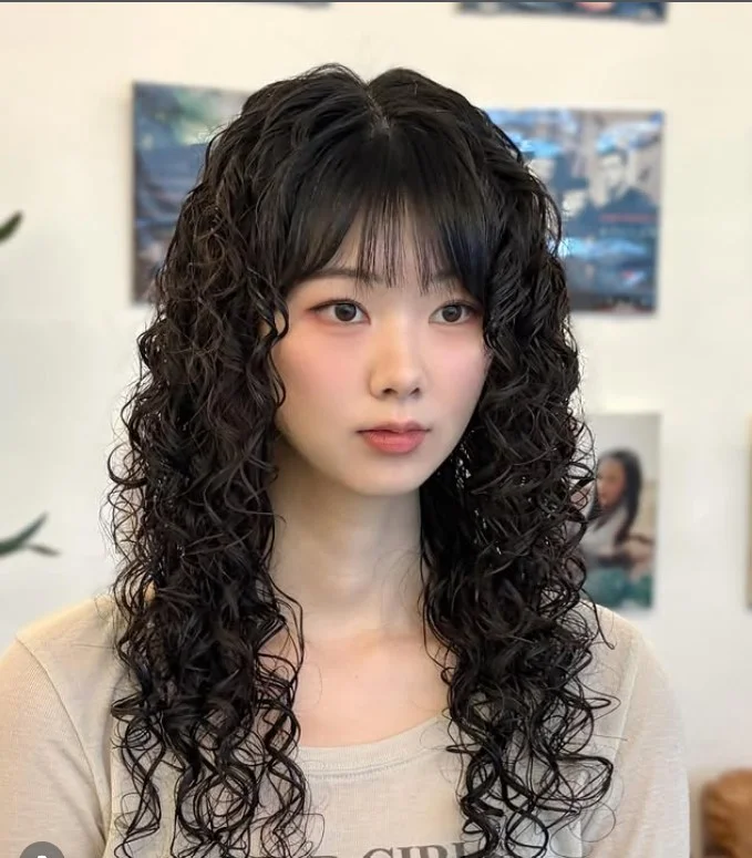 Curly hair with bangs hairstyle adding volume for long face