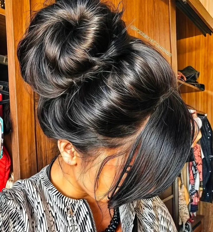 Face framing bun hairstyle with side bangs flattering soft look