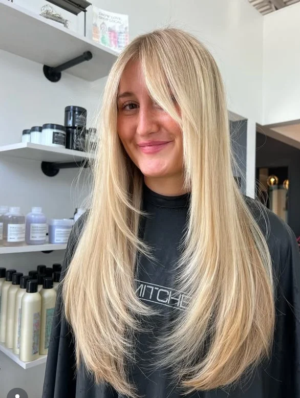Long blonde layered hairstyle with side bangs bright soft style