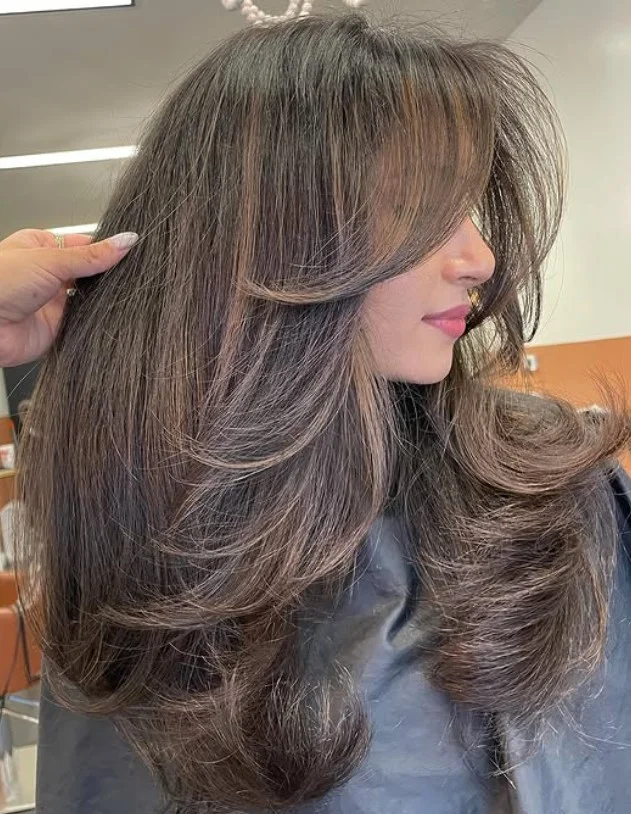 Long brunette layered hairstyle with side swept bangs glossy elegant look