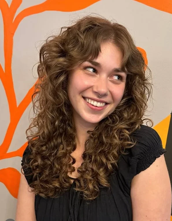 Natural curly hairstyle with side swept bangs soft face framing curls