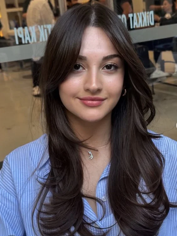 Straight long layered hairstyle with curtain bangs sleek polished finish