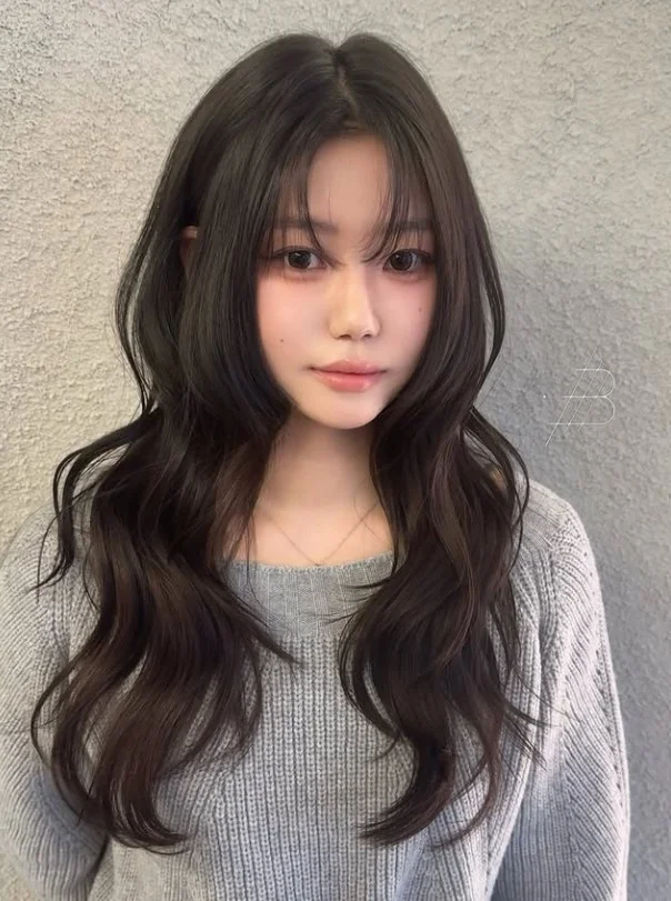 Wavy hair with wispy curtain bangs romantic textured hairstyle