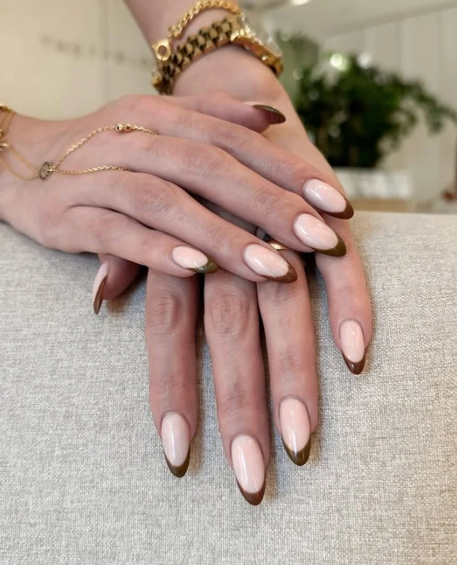 Modern almond nails with dark brown French tips and natural base.