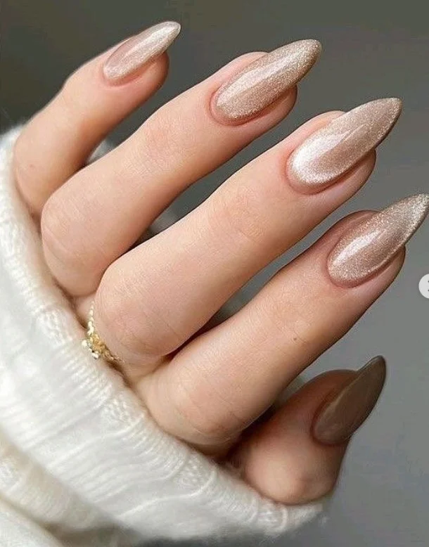 Champagne shimmer almond nails with subtle sparkle and classy neutral tones.