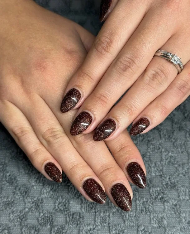 Dark brown almond nails with subtle cocoa glitter sparkle design.