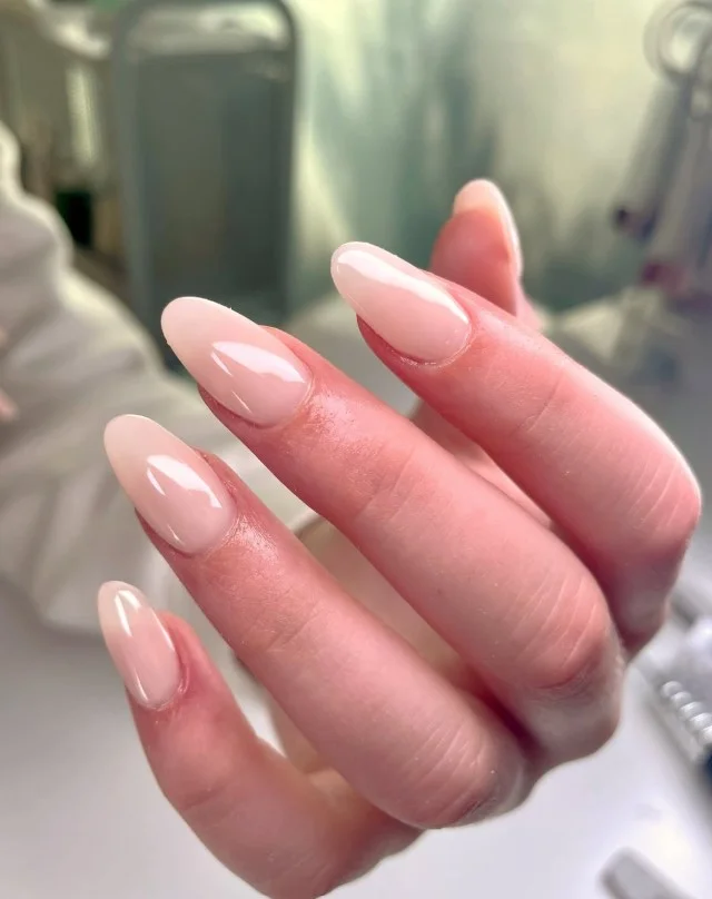 Elegant classy almond nail designs featuring soft nude polish with glossy finish