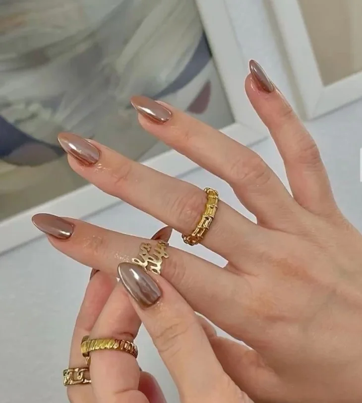 Glazed latte almond nails with a shiny pearl finish and trendy neutral color.