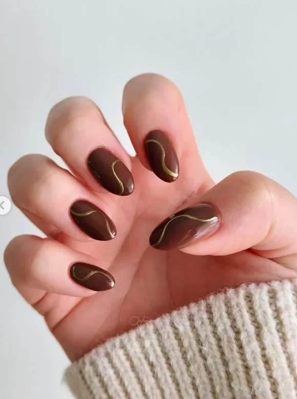 Dark brown almond nails with gold accent details for luxury look.