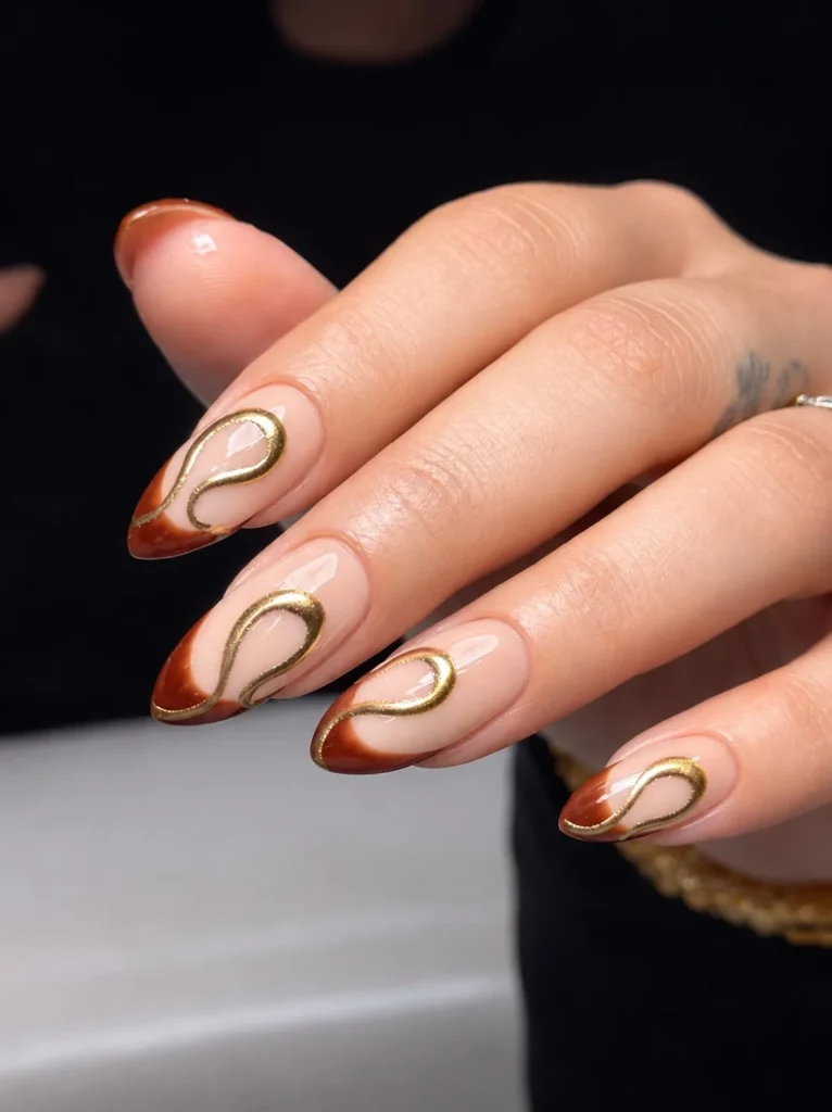 Light brown almond nails with delicate gold accents and elegant details.