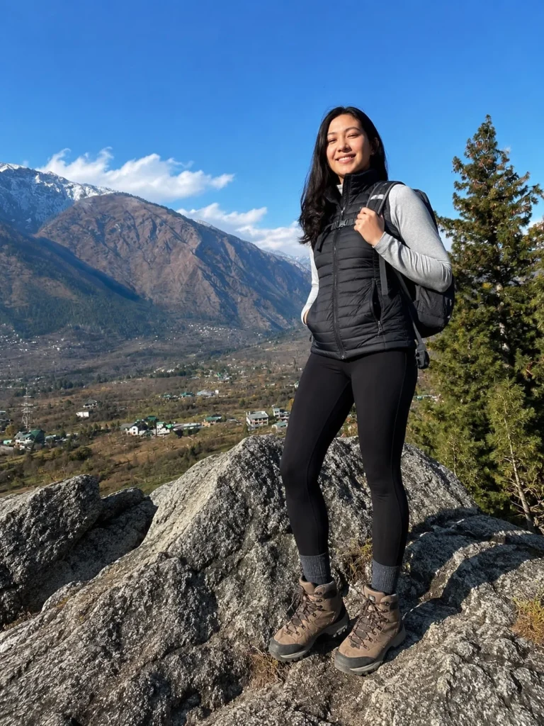 Lightweight puffer vest layered over trekking leggings for cool mountain hikes.