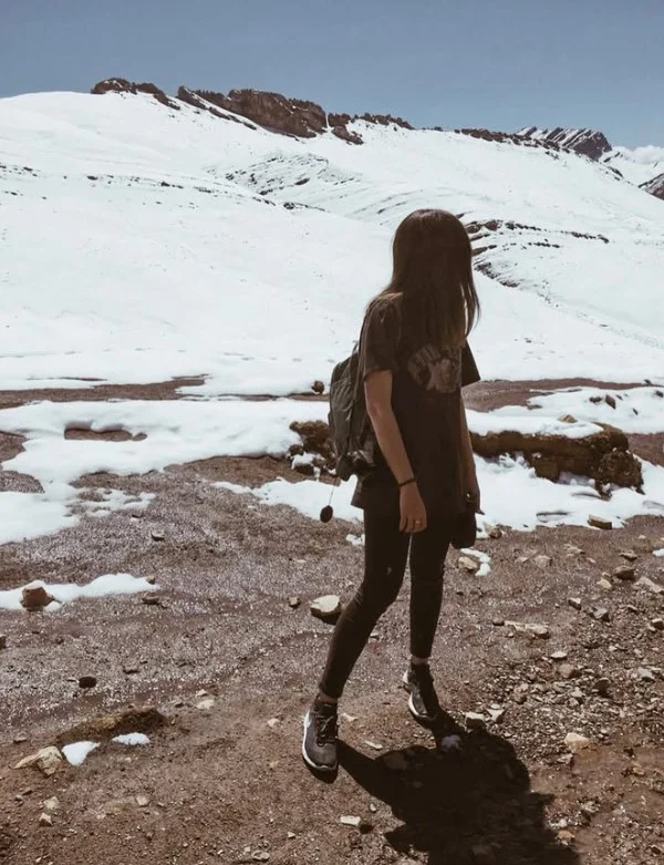 Woman wearing a moisture-wicking hiking shirt with black trekking leggings on a mountain trail.