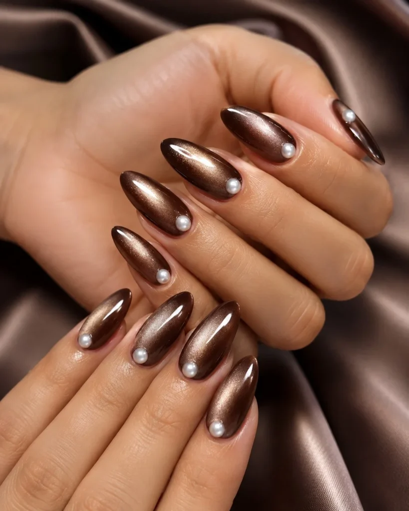 Soft pearl glow brown almond nails with shiny elegant reflection.