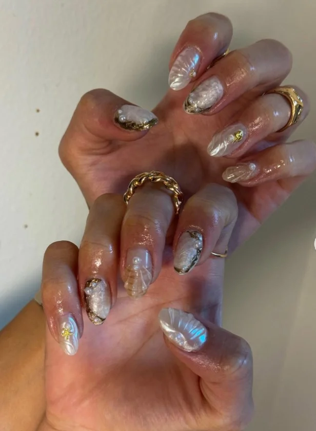 Summer 3D nail designs featuring tiny seashells and pearl accents on a beach-inspired manicure.