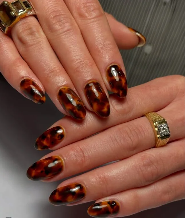 Tortoiseshell pattern almond nails with warm brown tones.