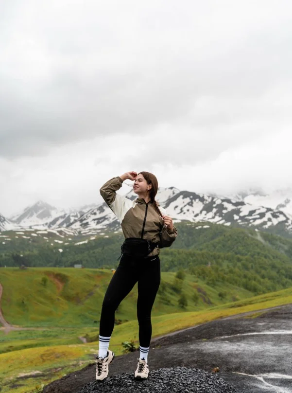Water-resistant windbreaker jacket paired with black hiking leggings for mountain trekking.