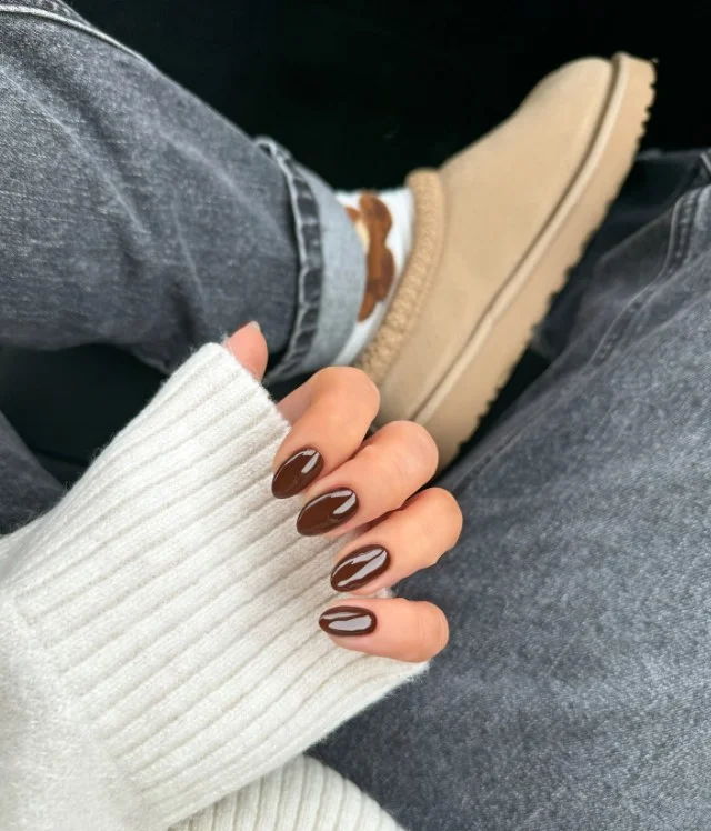 Chocolate brown nail polish complementing pale skin tones