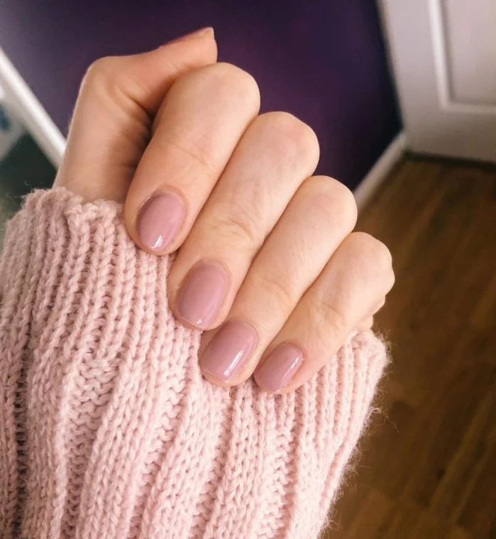 Dusty rose nails on pale skin with an elegant glossy finish