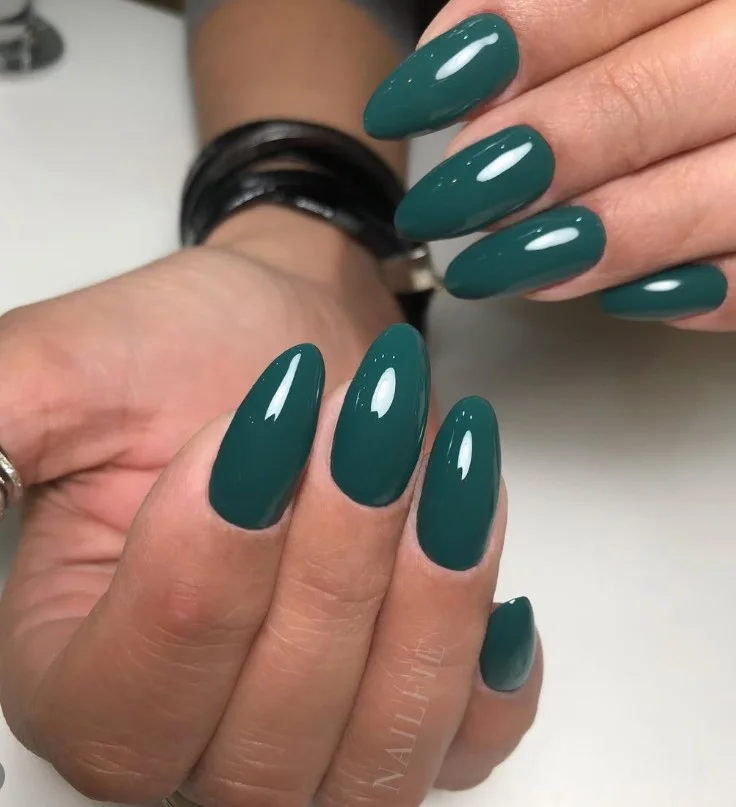 Emerald green nail polish adding a rich look to tan skin