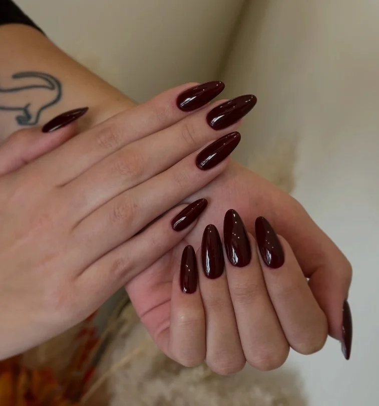 Burgundy almond fall nail designs featuring a soft tapered shape with a rich glossy finish.