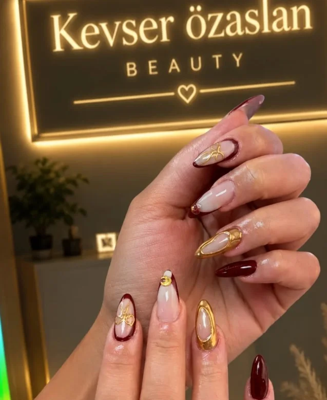 Burgundy fall nail designs decorated with delicate gold foil accents for a sophisticated autumn manicure.