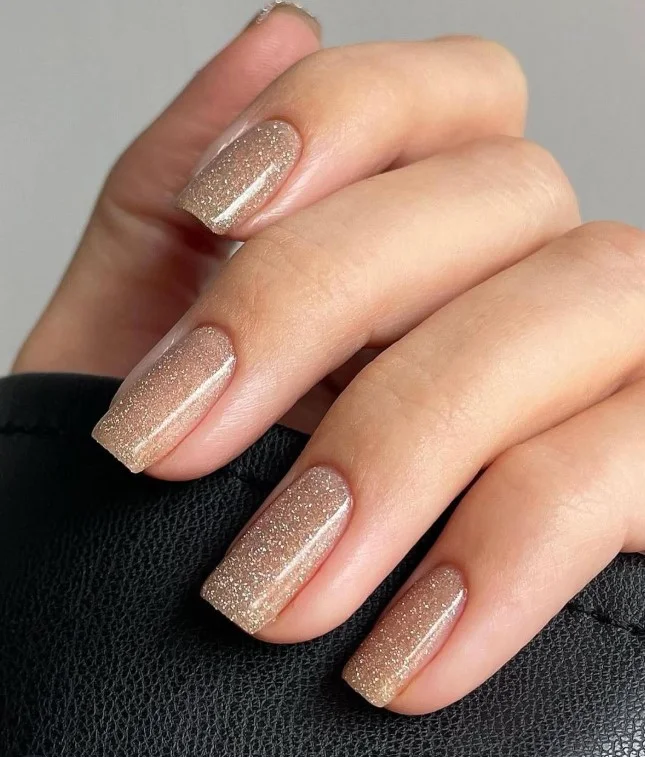 Fine champagne glitter nails paired with a green dress for special celebrations.