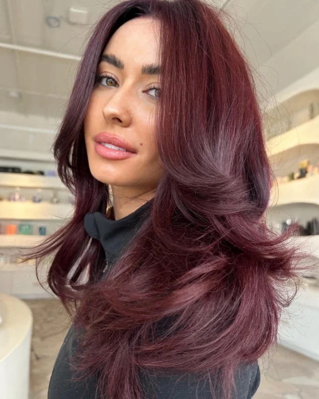 Deep cherry cola red hair creating rich contrast against porcelain skin.