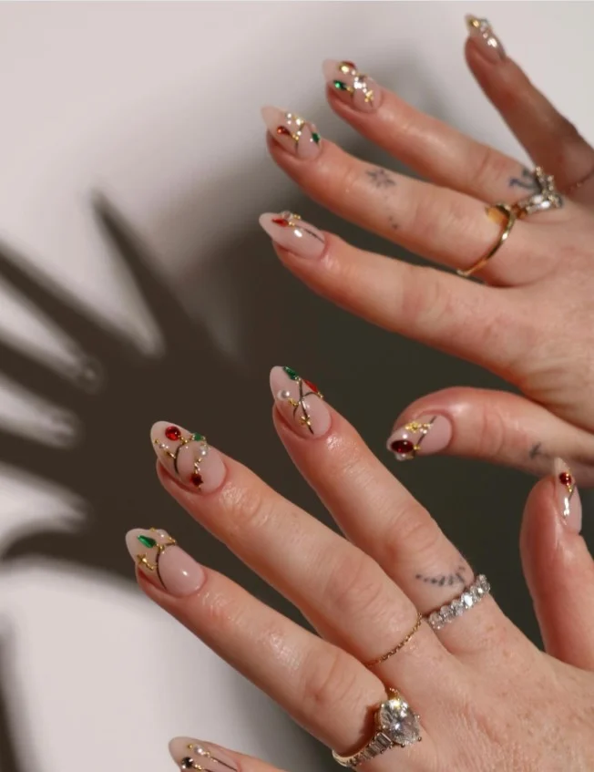 Cute Christmas nail designs decorated with metallic Christmas ornament details on elegant nude nails.