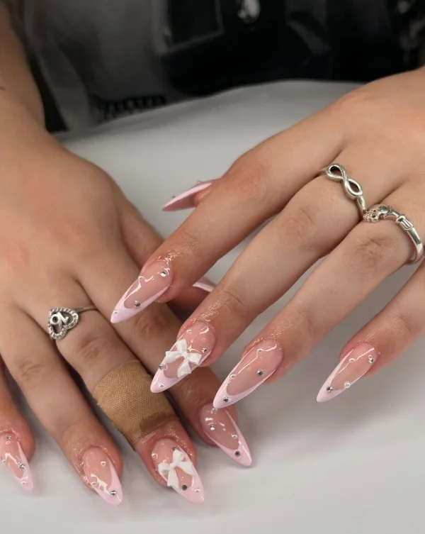 Cute coquette pink nail designs with elegant 3D bow accents on glossy pink nails.