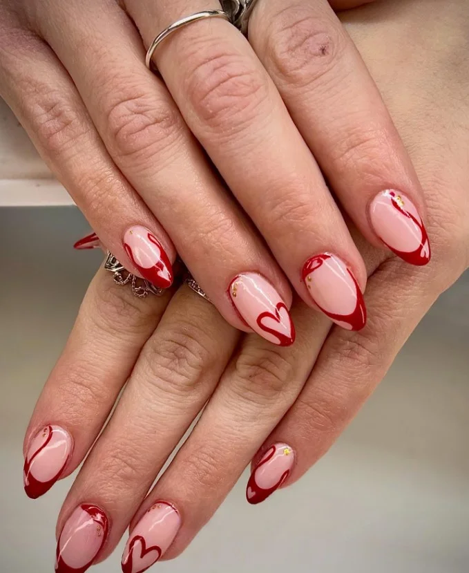 Cute red and nude nail designs with flowing swirl nail art on a glossy neutral base.