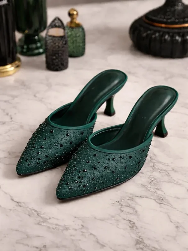 Emerald green heels creating a bold contrast with a simple black dress.