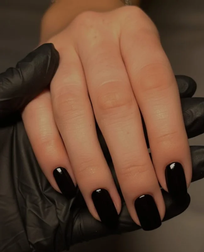 Glossy black nails paired with a dark green formal dress.