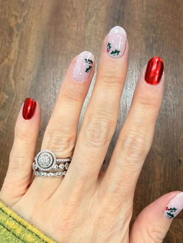 Cute Christmas nail designs featuring green holly leaves and bright red berries on a soft nude base.