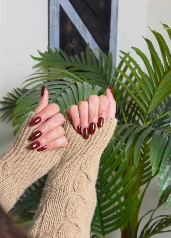 Long cherry red acrylic nails with a rich glossy finish for a timeless elegant manicure.