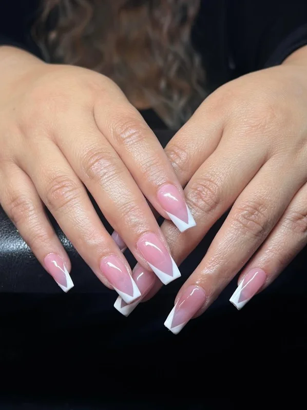 Long square acrylic nails featuring modern V-cut French tips on a glossy nude base.