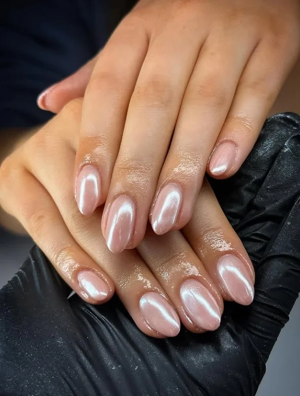 Milky pink nail designs finished with a delicate pearl chrome glow for a luxurious polished look.
