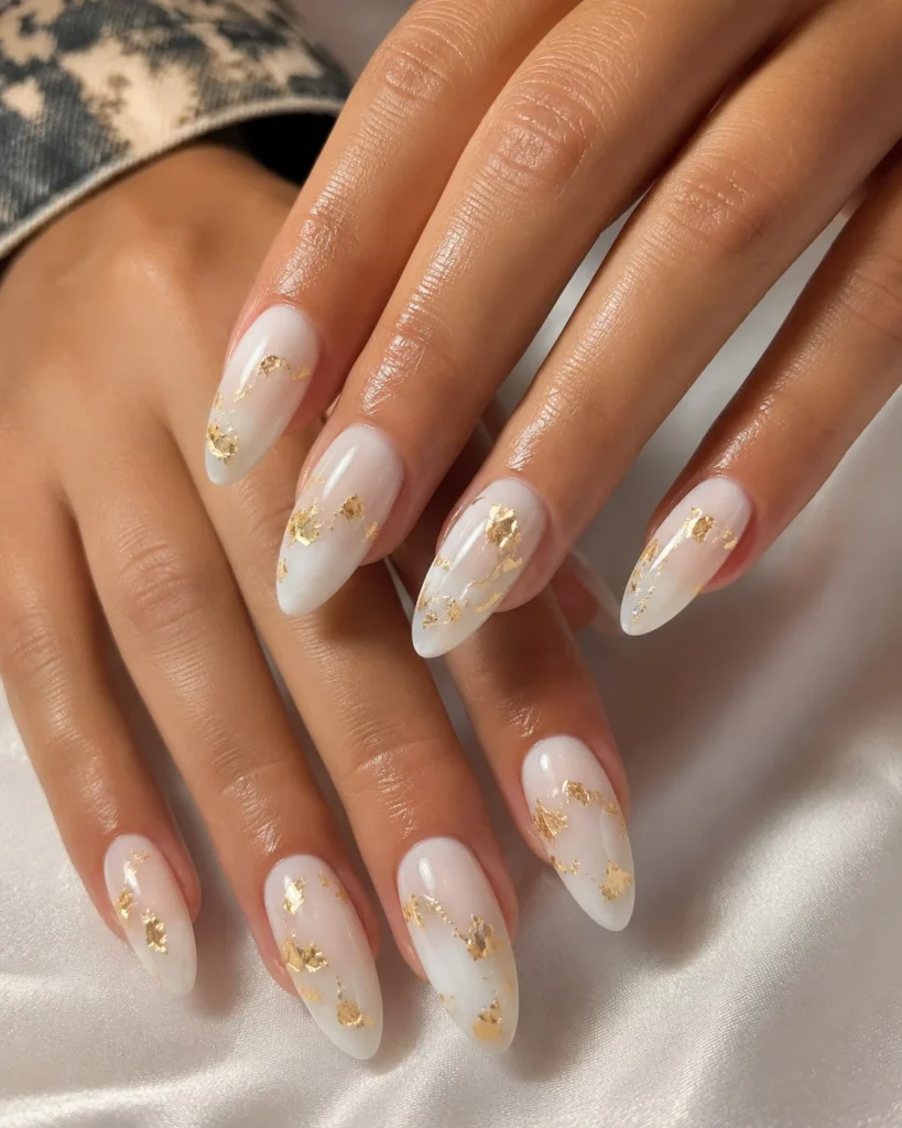 Milky white long nails finished with delicate gold foil accents for a luxurious nail design.