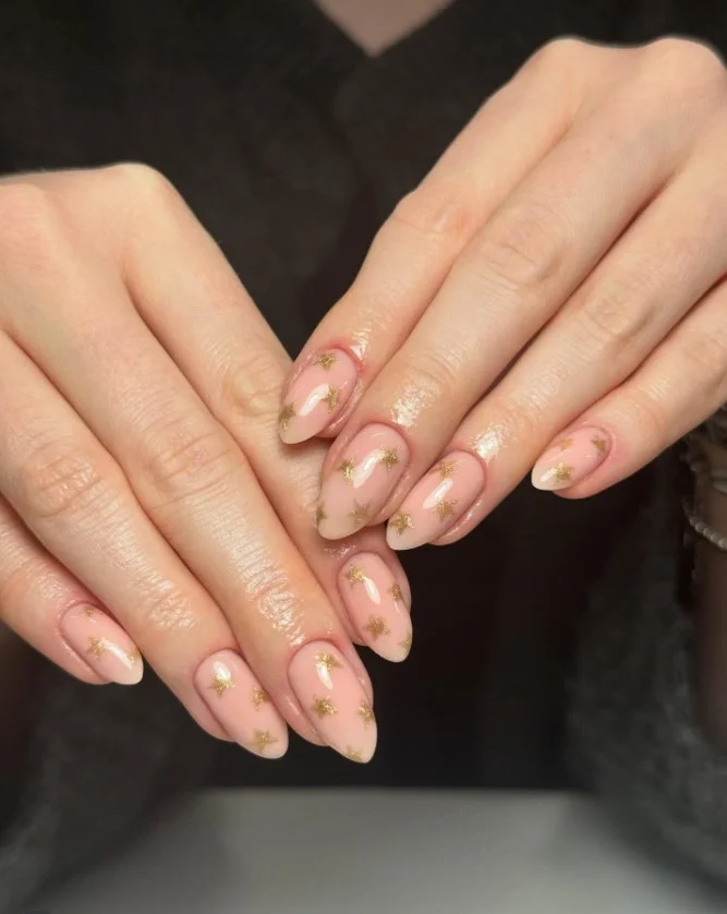 Cute Christmas nail designs with tiny gold stars over a milky nude base for a simple festive manicure.