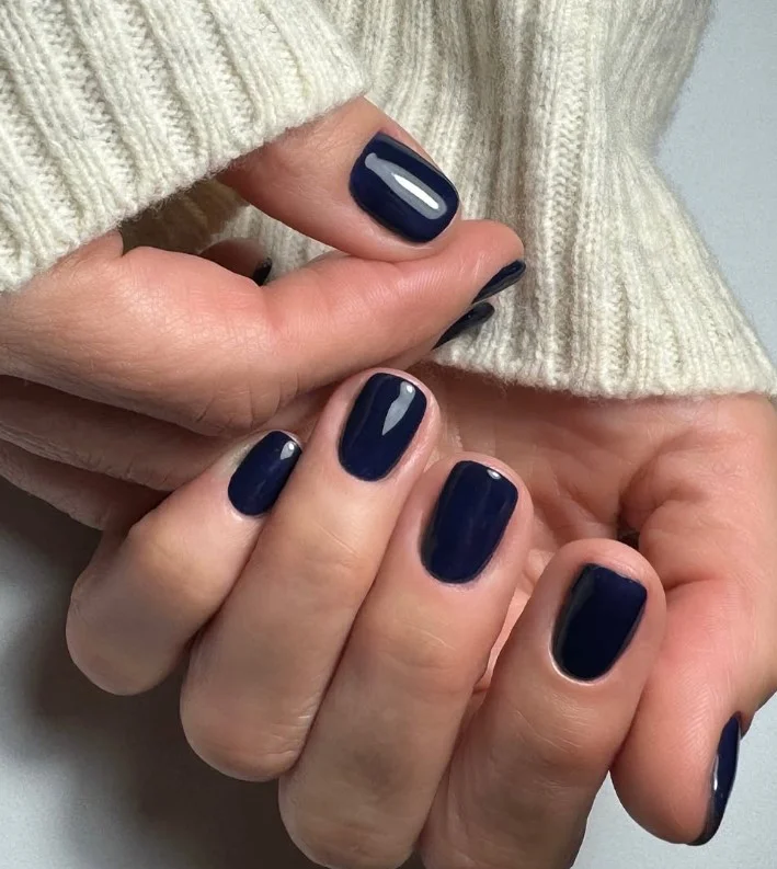 Deep navy manicure styled with an emerald green dress for a polished look.