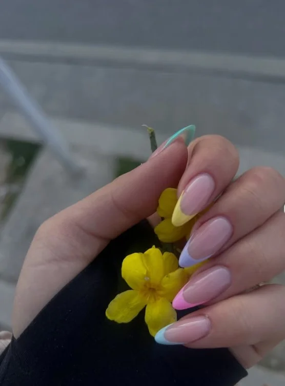 Long nails featuring soft pastel rainbow French tips over a natural pink nail base.