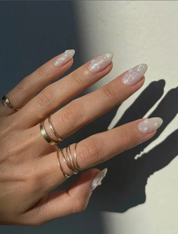 Pearl finish nails complementing a satin green dress for elegant occasions.
