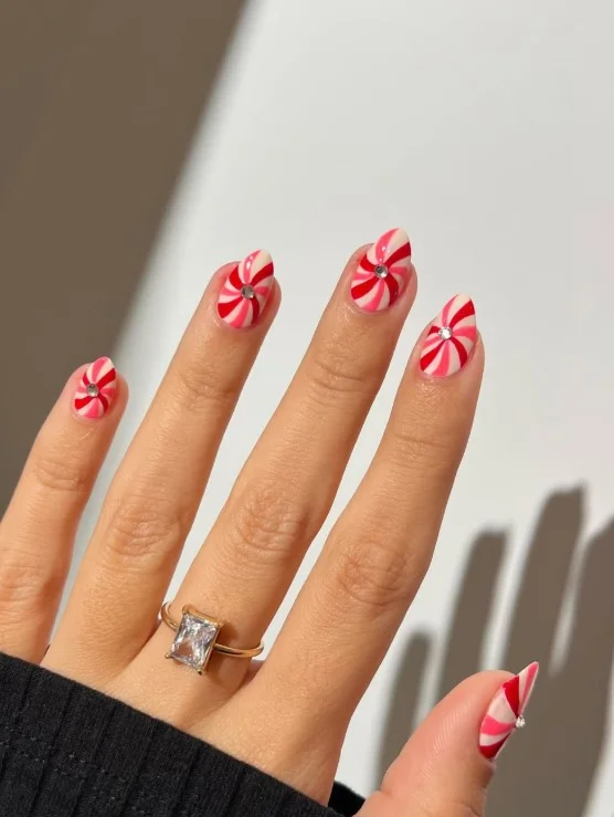 Cute Christmas nail designs with flowing peppermint swirl patterns inspired by classic holiday candy.